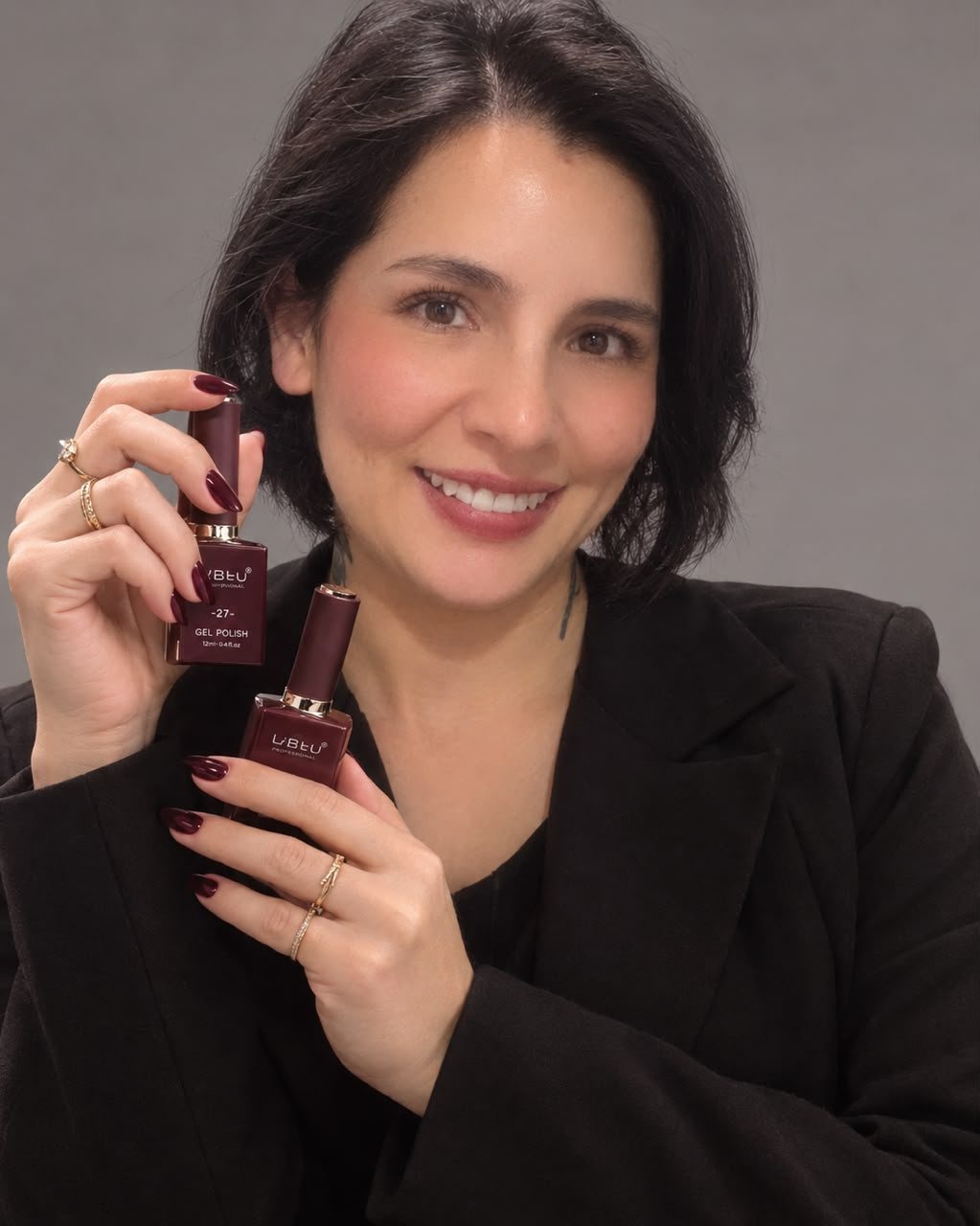 Malú sosteniendo dos esmaltes en tono vino